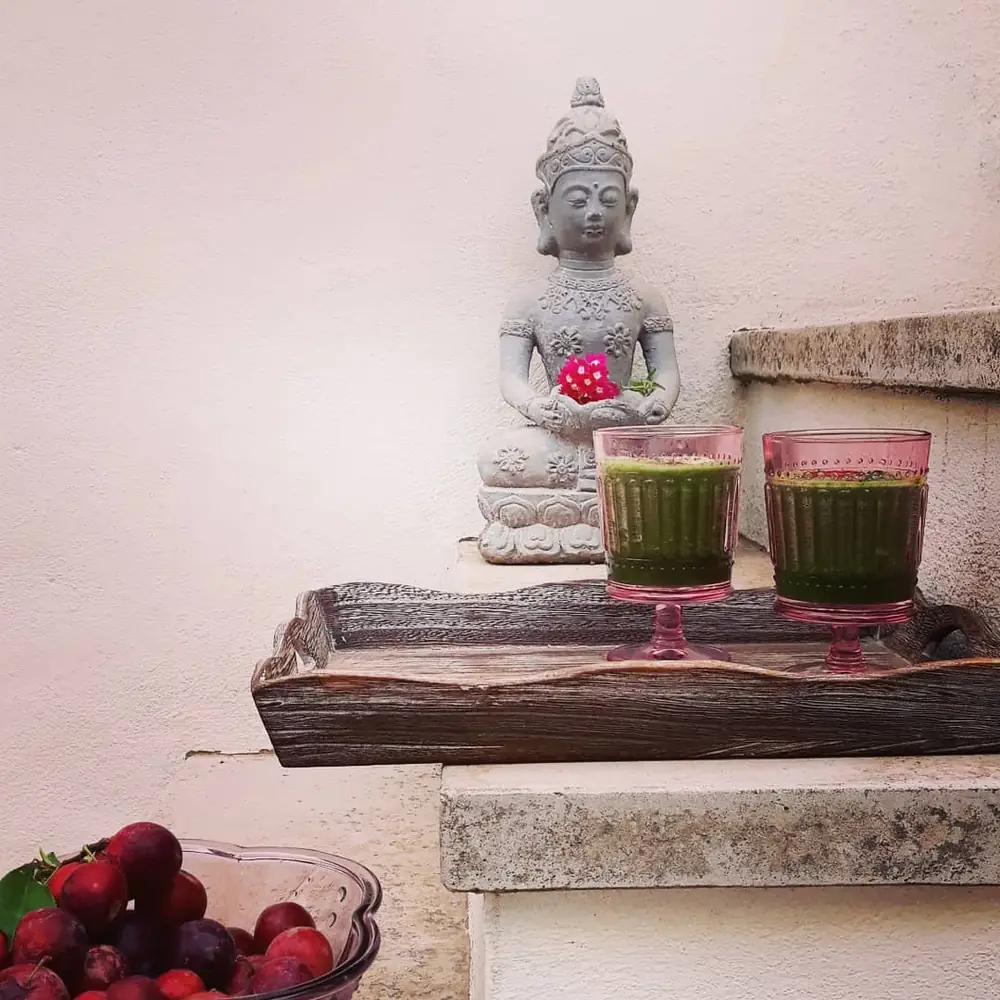 Buddha-Figur mit grünen Smoothies im Studio-Ambiente